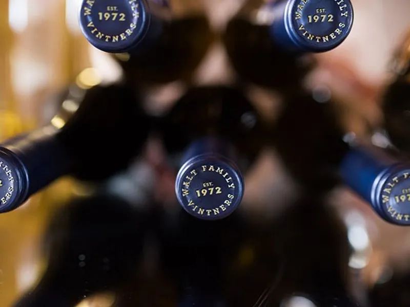 Bottle tops in a rack, each capsule stamped with the family seal