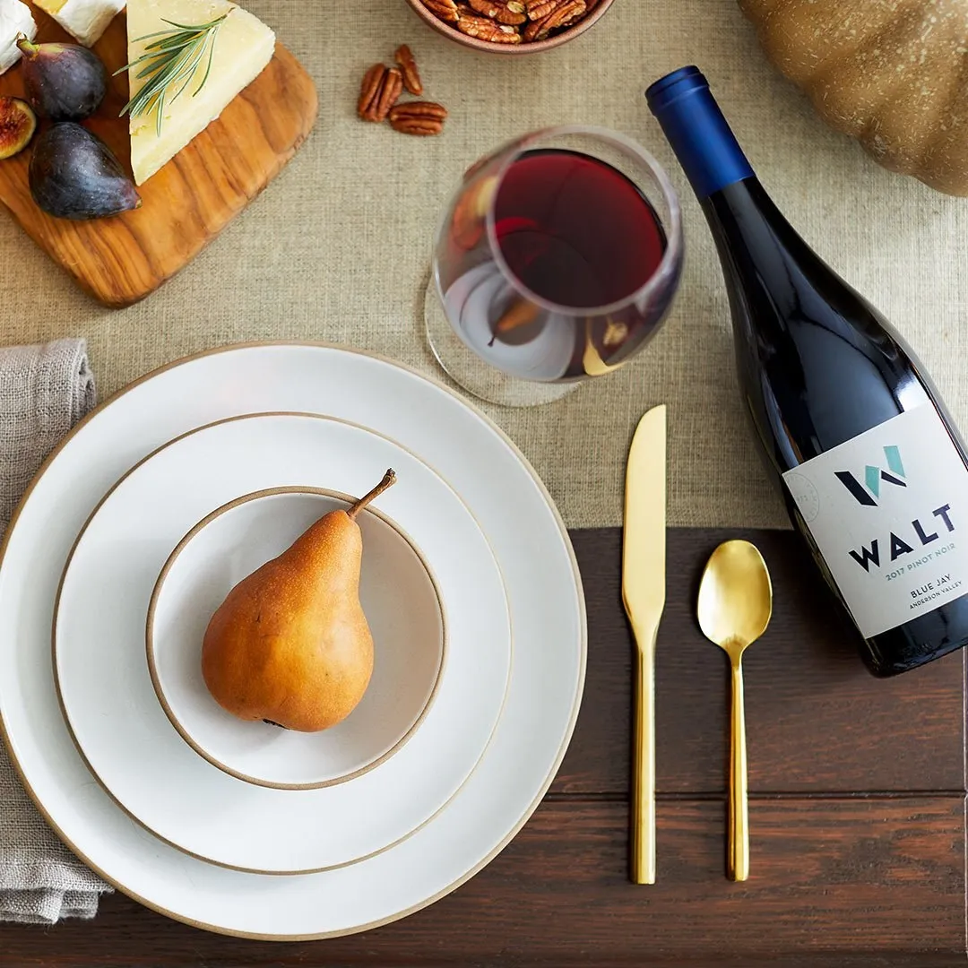 A place setting with a pear, a glass of Pinot and a bottle of Blue Jay Pinot Noir
